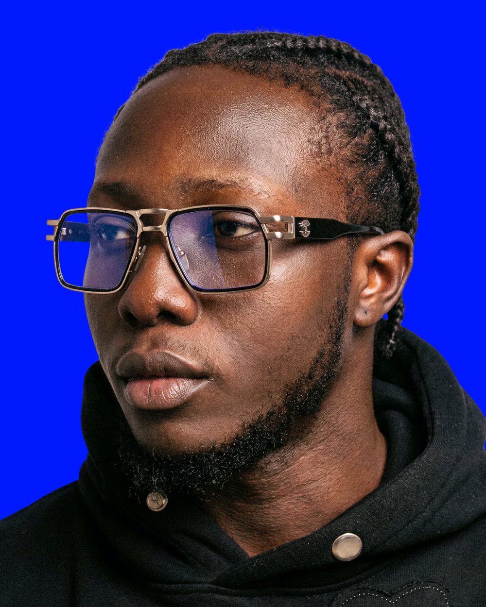 Nigel, editor, in gold-framed glasses against an electric-blue backdrop